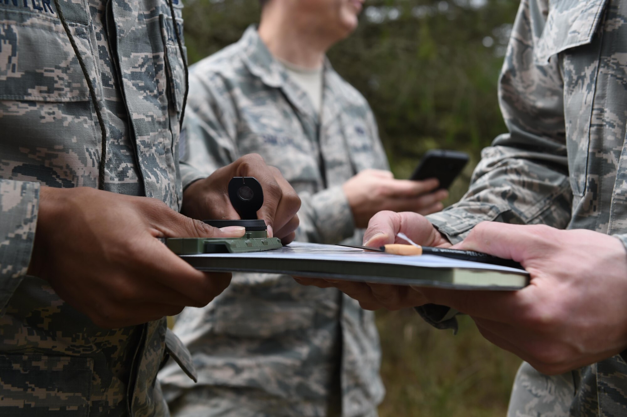 Airmen from the 627th Civil Engineer Squadron hold an azimuth and map during land navigation training on Joint Base Lewis-McChord, Wash., Feb. 16, 2017. The 627th CES typically conducts joint land navigation and convoy training with the Army prior to deployments where they will be working outside the wire, but this time they teamed up with the 627th Security Forces Squadron. (U.S. Air Force photo/Staff Sgt. Naomi Shipley)