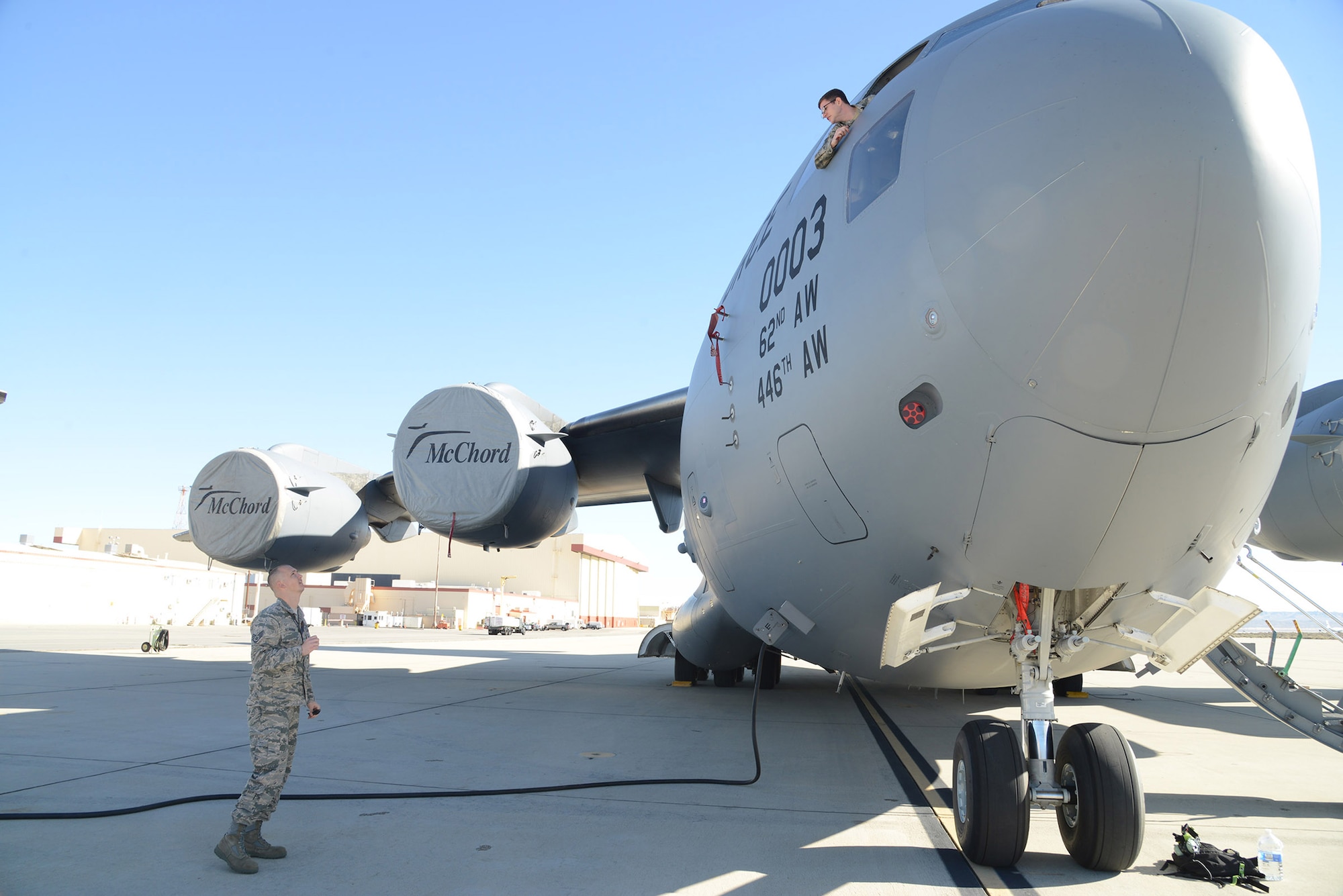 Staff Sgt. Steven Schrader (left) and Staff Sgt. Alex Rini, 412th Logistics Test Squadron, discuss the progress of the C-17 portion of the Hybrid Electric Flightline Cart Technology Pathfinder tests. The nearly zero noise of the HEF allows maintainers to converse without the use of the aircraft’s internal communication system. (U.S. Air Force photo by Christopher Ball)