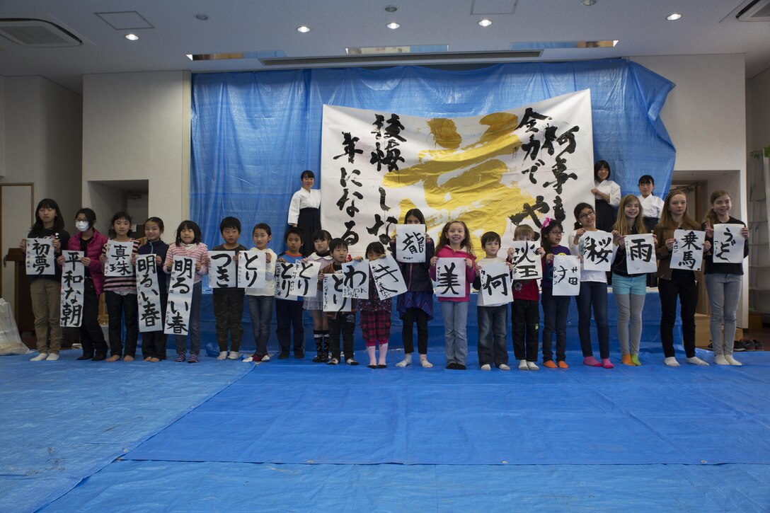 Children from Marine Corps Air Station Iwakuni and Japanese local children pose for a photo with their completed art work during a calligraphy event in Waki Town, Japan, Jan. 7, 2017. The children learned how to write their goals in Kanji for the new year. Similar to the American tradition of New Year’s resolutions, the Japanese use calligraphy to write their goals at the beginning of every new year.   (U.S. Marine Corps photo by Lance Cpl. Joseph Abrego)