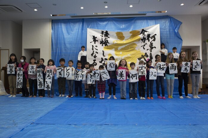 Children from Marine Corps Air Station Iwakuni and Japanese local children pose for a photo with their completed art work during a calligraphy event in Waki Town, Japan, Jan. 7, 2017. The children learned how to write their goals in Kanji for the new year. Similar to the American tradition of New Year’s resolutions, the Japanese use calligraphy to write their goals at the beginning of every new year.   (U.S. Marine Corps photo by Lance Cpl. Joseph Abrego)