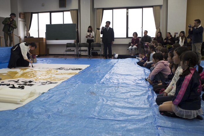 Marine Corps Air Station Iwakuni residents and Japanese locals watch as a member of the Otake Senior High School performs calligraphy in Waki Town, Japan, Jan. 7, 2017. Similar to the American tradition of New Year’s resolutions, the Japanese use calligraphy to write their goals at the beginning of every new year.  (U.S. Marine Corps photo by Lance Cpl. Joseph Abrego)