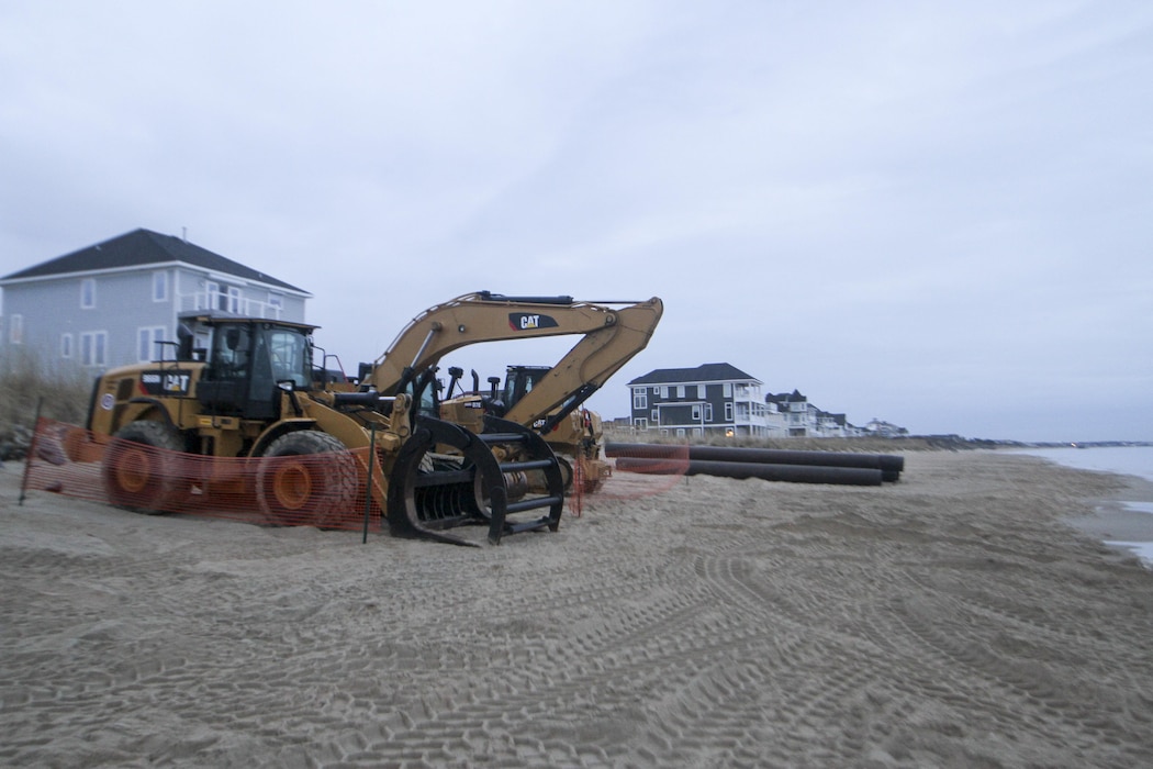 Heavy equipment is staged along the beach in Norfolk, Virginia’s East Ocean View neighborhood. Contractors will use the equipment to move dredged up sand on the beach to create a 60 foot wide beach berm that slopes to 5 feet above mean low water. Engineers’ designed the beach to absorb the wave energy, protecting critical infrastructure during coastal storms. (U.S. Army photo/Patrick Bloodgood)