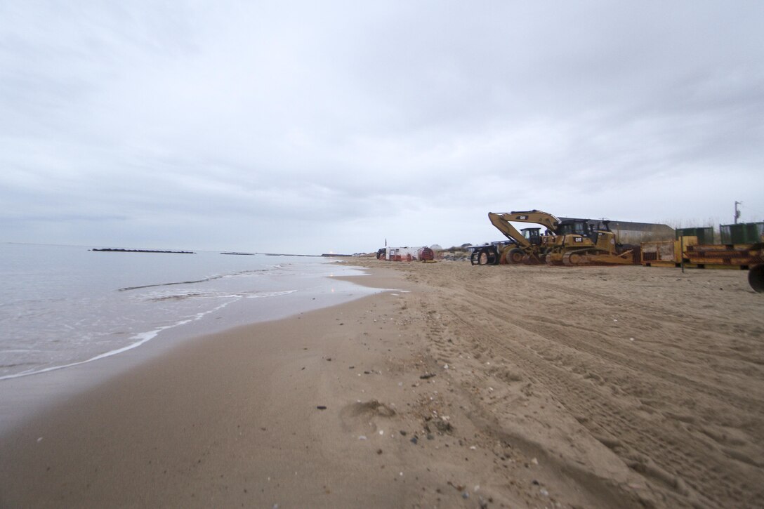 Heavy equipment is staged along the beach in Norfolk, Virginia’s East Ocean View neighborhood. Contractors will use the equipment to move dredged up sand on the beach to create a 60 foot wide beach berm that slopes to 5 feet above mean low water. Engineers’ designed the beach to absorb the wave energy, protecting critical infrastructure during coastal storms. (U.S. Army photo/Patrick Bloodgood)