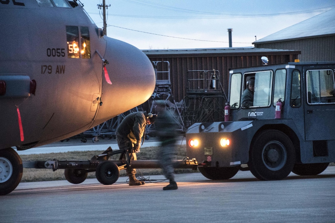 Airmen hook up C-130H Hercules before moving it out of a hangar  as the sun rises over Mansfield Lahm Air National Guard Base, Mansfield, Ohio, Feb. 21, 2017. Air National Guard photo by 1st Lt. Paul Stennett  