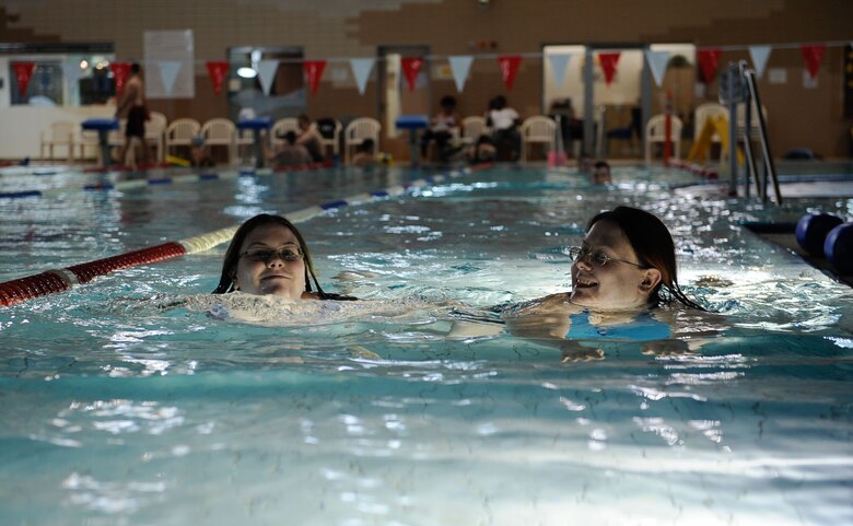 Christina Moore(right), wife of Gary Moore, U.S. Air Forces in Europe visual information specialist, smiles at her daughter, Samantha(left), as they swim at the Aquatic Center on Ramstein Air Base, Germany, Feb. 14, 2017. The Biggest Loser challenge has given both women a steady workout plan and diet that they are excited to say feels right for them. (U.S. Air Force photo by Airman 1st Class Savannah L. Waters)