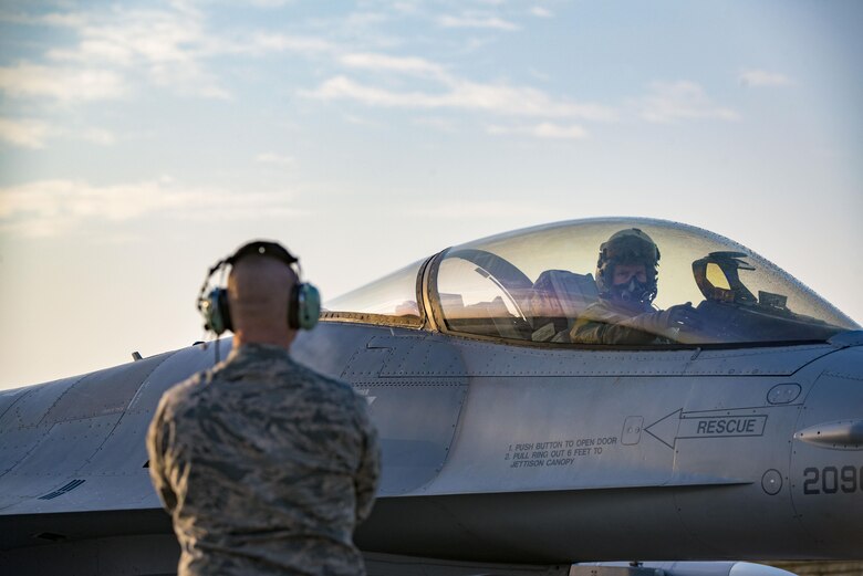 Airman 1st Class Austin Bennett, 31st Aircraft Maintenance Squadron assistant dedicated crew chief, guides Brig. Gen. Lance Landrum, 31st Fighter Wing commander, off the taxiway prior to takeoff at Aviano Air Base, Italy, Feb. 17, 2017. The general flew with 555th Fighter Squadron F-16 pilots to train with 2nd Air Support Operations Squadron joint tactical air controllers on close-air support operations like air-to-ground weapon strikes. (U.S. Air Force photo by Senior Airman Cory W. Bush)