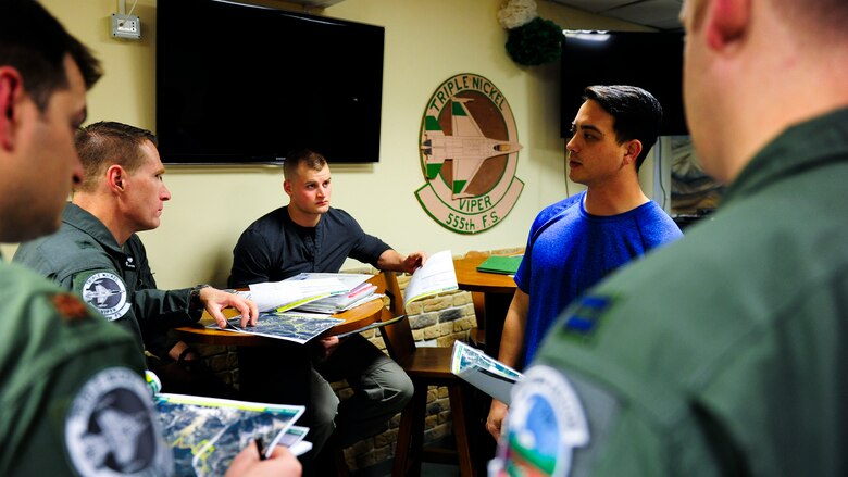 Senior Airman Mark Brush, 2nd Air Support Operations Squadron joint tactical air controller, in blue, briefs F-16 Fighting Falcon pilots from the 555th Fighter Squadron and Airman 1st Class Jeremy Mootz, 31st Medical Support Squadron medical logistics technician, center left, before a routine training mission at Aviano Air Base, Italy, Feb. 17, 2017. Mootz shadowed a JTAC team to educate him on JTAC operations. Mootz was selected for retraining as an Air Liaison Officer, which is a commissioned position as a JTAC. (U.S. Air Force photo by Staff Sgt. Austin Harvill)