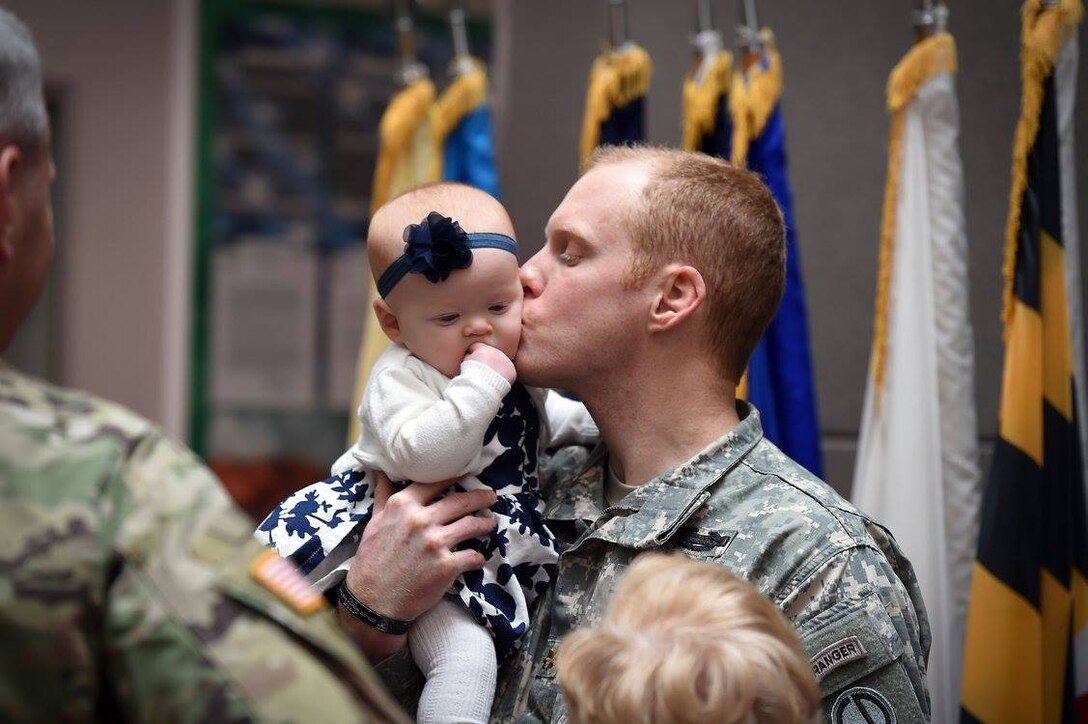Maj. Russell Litko, outgoing Headquarters and Headquarters Company commander, 85th Support Command, kisses his daughter during his Change of Command ceremony, Feb. 12, 2017. 
(Photo by Sgt. Aaron Berogan)