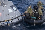 U.S. Navy divers and other personnel in a Zodiac boat secure a harness around a test version of the Orion crew module during Underway Recovery Test 5 in the Pacific Ocean off the coast of California on Oct. 28, 2016. Members of the New York Air National Guard's 106th Rescue Wing will participate in a mission in Hawaii designed to test space capsule recovery techniques and equipment, although they will not work with a capsule simulator like this one.Orion is the exploration spacecraft designed to carry astronauts to destinations not yet explored by humans. 