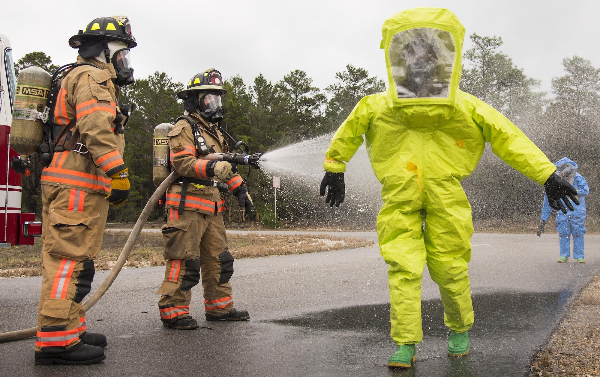 Firefighters from the 96th Test Wing hose down Airmen as part of the decontamination process at the end of a hazardous material portion of an exercise Feb. 22 at Eglin Air Force Base, Fla.  The chemical, biological, nuclear response exercise tested the procedures of emergency response, explosive ordnance disposal, emergency management and bioenvironmental agencies among others.  (U.S. Air Force photo/Samuel King Jr.)