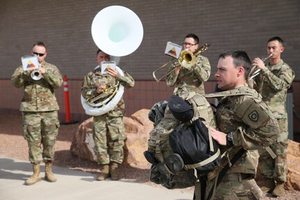 As members of the 1st Armored Division Band play, Soldiers assigned to the 207th Engineer Company, Kentucky Army National Guard, and the 215th Engineer Company, Puerto Rico Army National Guard, begin boarding an aircraft at the Silas L. Copeland Arrival/Departure Airfield Control Group here Feb. 2 for a deployment in support of Operation Freedom’s Sentinel.