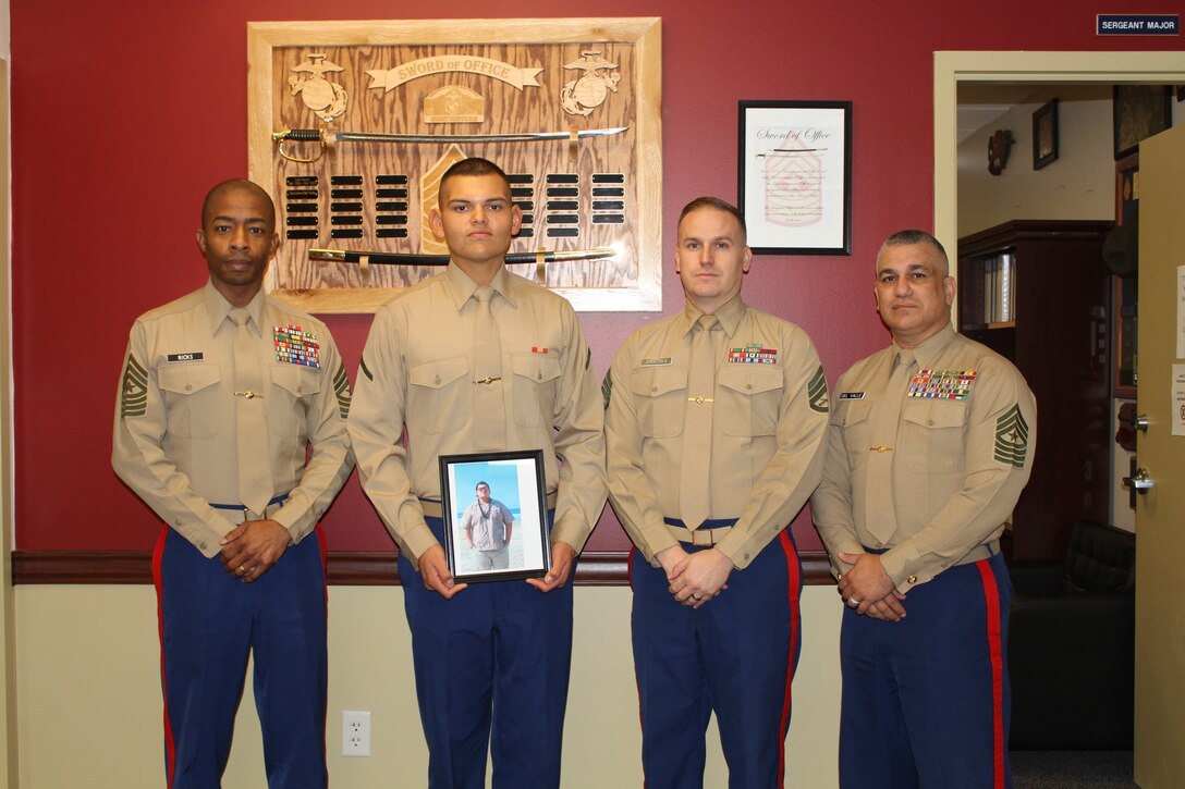 Pfc. John M. Hinajosa Jr. holds a photo of himself prior to joining the Marine Corps as he stands with Sgt. Maj. Troy A. Nicks (left), Sgt. Maj. Marcelino Del Valle and Staff Sgt. David M. Panuska (right). Hinojosa, a New Braunfels, Texas native, lost 135 pounds in 8 months to become a United States Marine. Nicks is the Sergeant Major for the 8th Marine Corps District, Del Valle is the Sergeant Major for Recruiting Station San Antonio and Panuska is the noncommissioned officer in-charge of the office Hinajosa was recruited from, Recruiting Substation Northeast.
