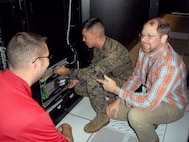 Jason Hessler (left) and Andy Collison (right), Automated Message Handling System support engineers, train a Marine from Marine Corps Installations East G-6 on the Hyper-Converged Infrastructure system Nov. 9, aboard Camp Lejeune, North Carolina. HCI is a virtualization solution that replaces traditional servers, and combines storage and compute functions into a single machine to save cost, energy and space. Marine Corps Systems Command’s Information Systems and Infrastructure recently installed the technology at Camp Lejeune, North Carolina, and Camp Pendleton, California, to support Organizational Messaging Service, which is used to send operational and administrative messages across the Corps. (Courtesy photo)