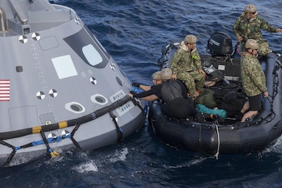 Navy divers and other personnel in a Zodiac boat secure a harness around a test version of the Orion crew module during Underway Recovery Test 5 in the Pacific Ocean off the coast of California, Oct. 28, 2016. Members of the New York Air National Guard's 106th Rescue Wing will participate in a mission in Hawaii designed to test space capsule recovery techniques and equipment, although they will not work with a capsule simulator like this one. Orion is the exploration spacecraft designed to carry astronauts to destinations not yet explored by humans. NASA photo