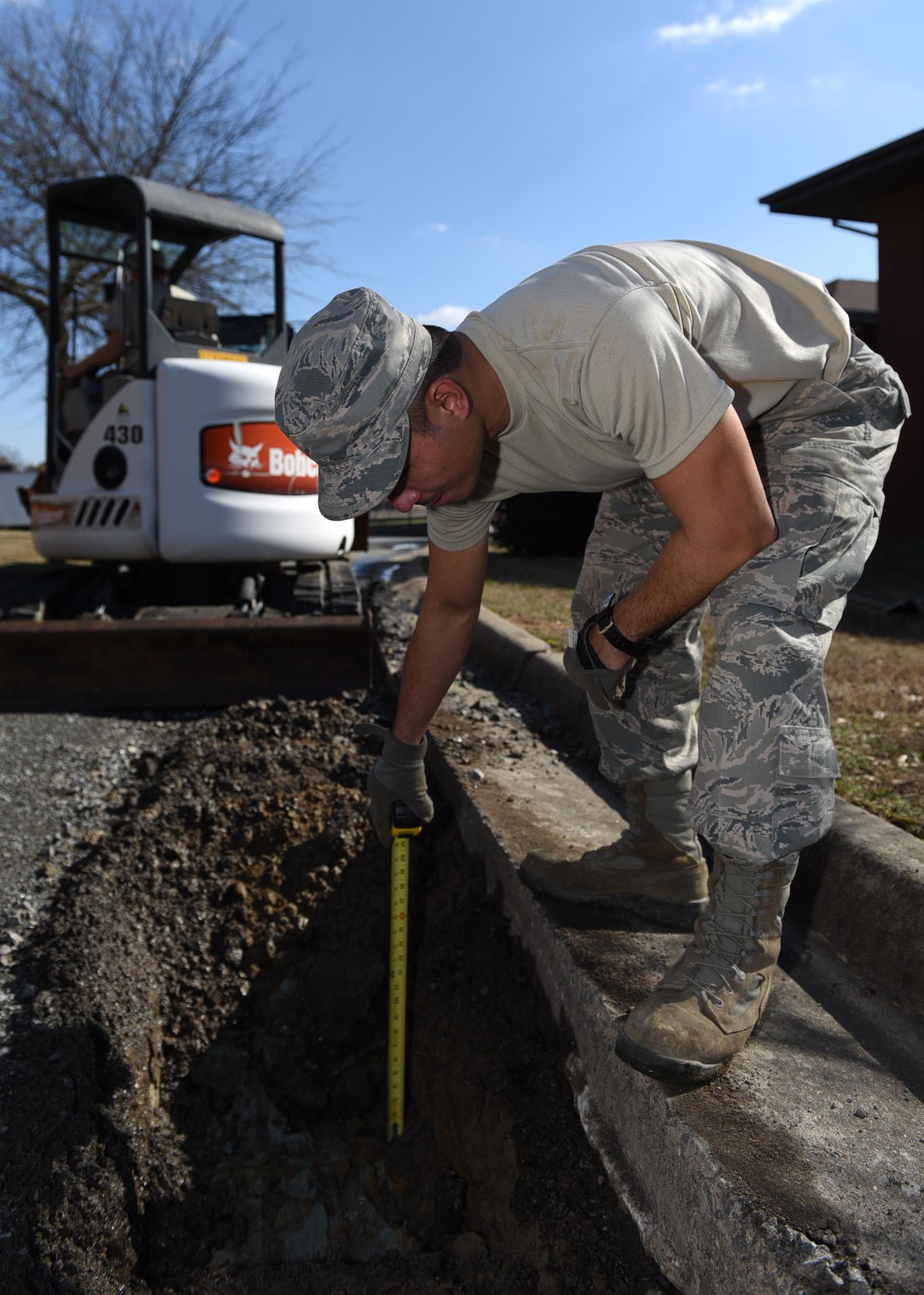 U.S. Air Force Senior Airman Allen Arceo, 19th Civil Engineer Squadron pavement and heavy equipment craftsman, measures the depth of an excavated subbase Jan. 7, 2017, at Little Rock Air Force Base, Ark. Measuring the depth ensures enough material is removed to allow the placement of ballast rock to help strengthen the area of the road. (U.S. Air Force photo by Airman 1st Class Kevin Sommer Giron)