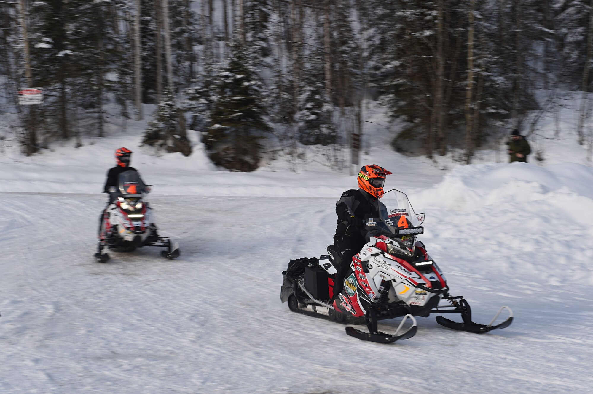 Snowmobile racers ride through trails at Joint Base Elmendorf-Richardson, Alaska, during the Iron Dog race Feb. 18, 2017. Military personnel and families gathered to high-five racers as they passed by Otter Lake. 