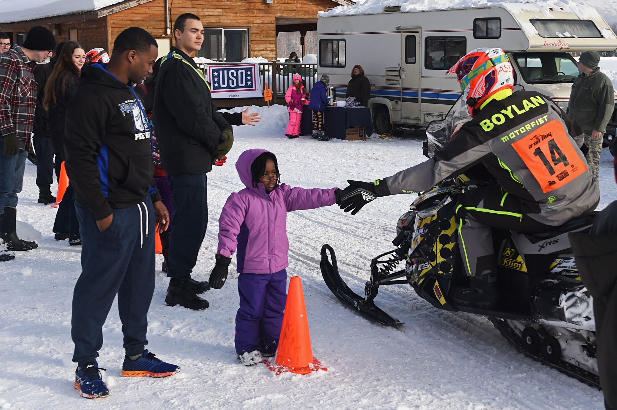A snowmobile racer high-fives Kourtney Allen, 5, at Joint Base Elmendorf-Richardson, Alaska, Feb. 18, 2017 during the Iron Dog race. Race participants cover some of Alaska’s most remote and rugged terrain while confronting some the harshest winter conditions. 