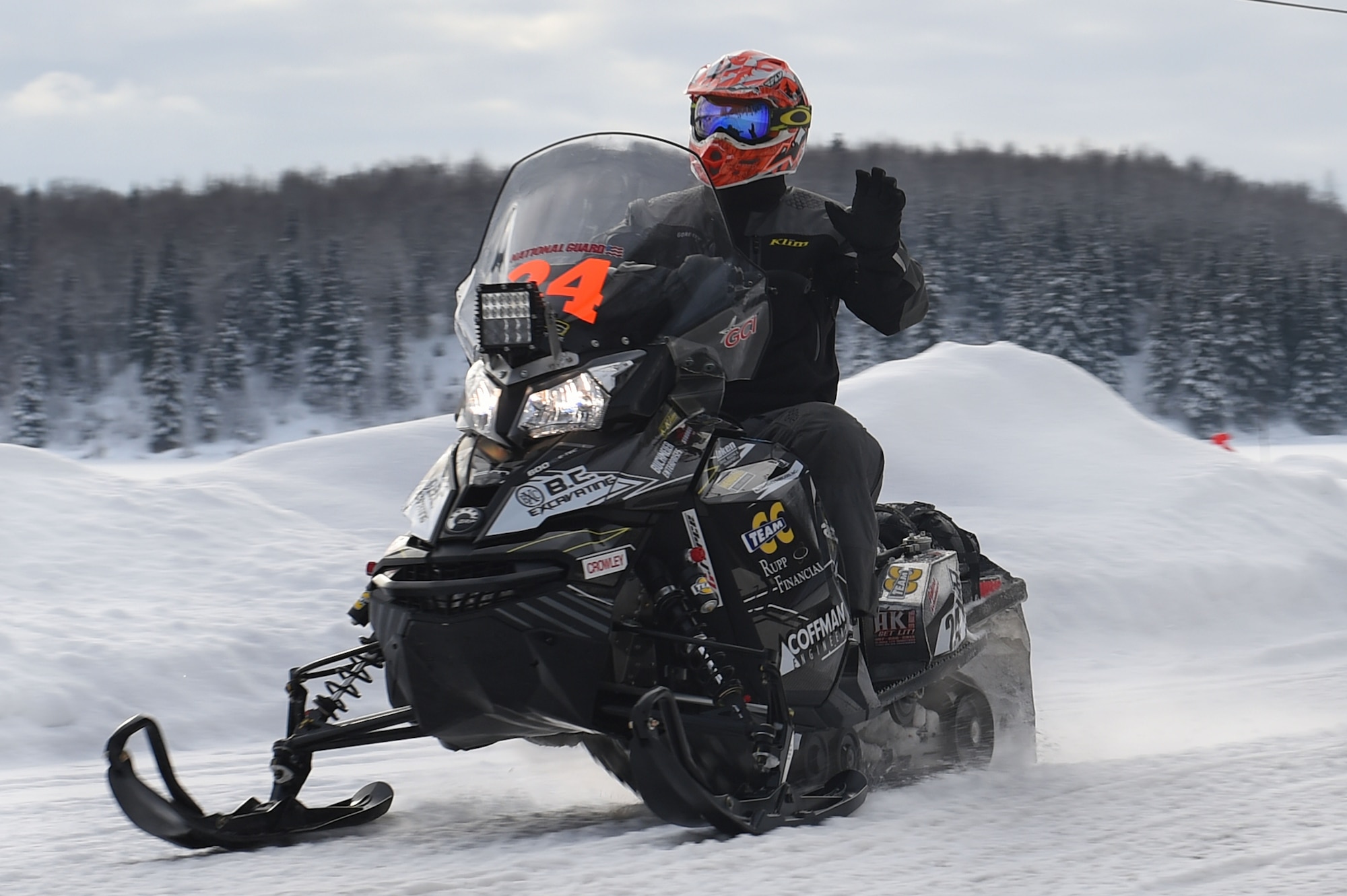 A snowmobile racer waves as he passes fans while riding through trails at Joint Base Elmendorf-Richardson, Alaska, during the Iron Dog race Feb. 18, 2017.Race participants cover some of Alaska’s most remote and rugged terrain while confronting some the harshest winter conditions. 