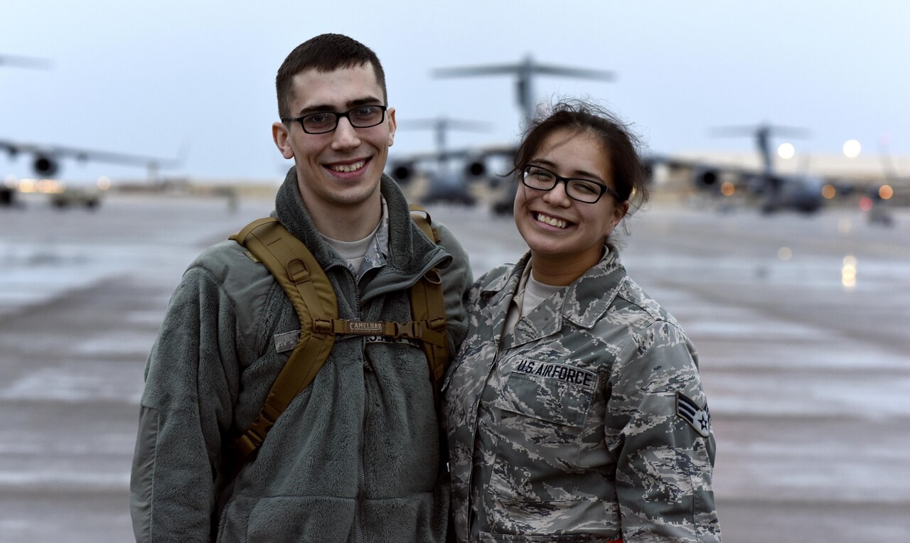 U.S. Air Force Senior Airman Matthew Feigum, a combat crew communications journeyman with the 816th Expeditionary Air Lift Squadron, left, and U.S. Air Force Senior Airman Sylvia Feigum, a combat oriented supply organization journeyman with the 8th Expeditionary Air Mobility Squadron, pose for a photo at Al Udeid Air Base, Qatar, Feb. 16, 2017. The Feigums posed for a photo after Sylvia marshaled in the rotator Matthew arrived on.  (U.S. Air Force photo by Senior Airman Cynthia A. Innocenti)