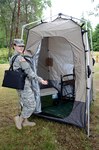 Spc. Brianne Kim of the Washington National Guard happily shows off a tent provided for nursing mothers.