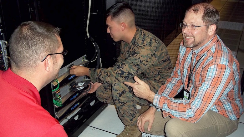 Jason Hessler (left) and Andy Collison (right), Automated Message Handling System support engineers, train a Marine from Marine Corps Installations East G-6 on the Hyper-Converged Infrastructure system Nov. 9, at Marine Corps Base Camp Lejeune, North Carolina. HCI is a virtualization solution that replaces traditional servers, and combines storage and compute functions into a single machine to save cost, energy and space. Marine Corps Systems Command’s Information Systems and Infrastructure recently installed the technology at Camp Lejeune, North Carolina, and Camp Pendleton, California, to support Organizational Messaging Service, which is used to send operational and administrative messages across the Corps. 