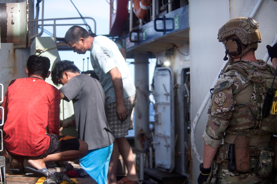 A Coast Guardsman stands watch as a foreign-flagged fishing vessel crew performs maintenance during an Oceania Maritime Security Initiative boarding mission in the Pacific Ocean, Feb. 17, 2017. Navy photo by Petty Officer 3rd Class Danny Kelley