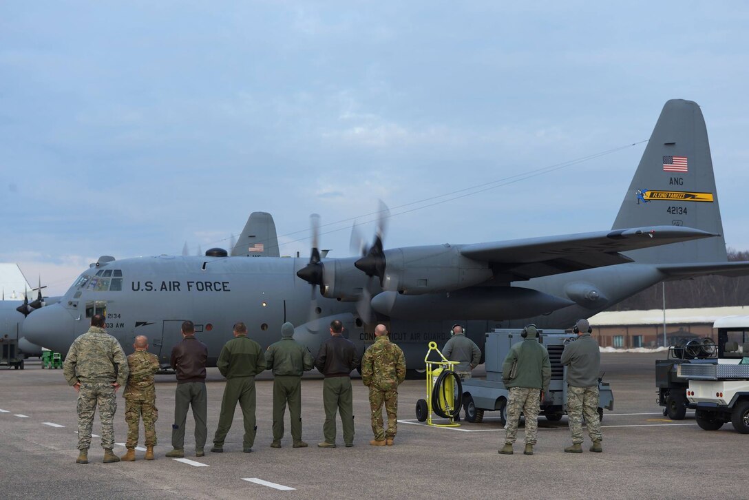 Leadership from the 103rd Airlift Wing and Connecticut National Guard stand in a row, awaiting the take-off of the 103rd's C-130 Hercules carrying deployers at Bradley Air National Guard Base, East Granby, Conn., Feb. 22, 2017. (U.S. Air National Guard photo by 2nd Lt. Jen Pierce)
