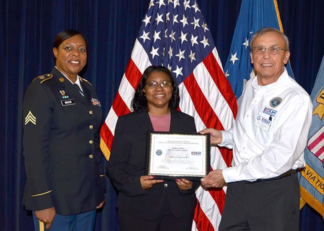 Defense Logistics Agency Information Operations’ Audrey Jones (center)  receives the Secretary of Defense, Employer Support of the Guard and Reserve’s Patriotic Employer Award from retired Army Lt. Col. Bob Sempek, ESGR Central Virginia Region military outreach volunteer Feb. 21 during a ceremony on Defense Supply Center Richmond, Virginia. Jones was nominated by her employee, Information Technology Specialist Monica Briscoe (left), who is also a sergeant in the Virginia Army National Guard.