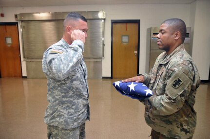 U.S. Army Reserve Soldiers Sgt. Luis Gonzalez, left, with the 365th Combat Support Sustainment Battalion (CSSB), 321st Sustainment Brigade, 143rd Expeditionary Sustainment Command, 377th Theater Sustainment Command, salutes a U.S. flag after presenting it to Sgt. 1st Class Jeremy Reed, with the 412th Theater Engineer Command, at the Command headquarters in Vicksburg, Miss., Jan. 20, 2017. The pair had just practiced removing the U.S. flag from a table instead of a casket and folding it 13 times into the shape of a symbolic tri-cornered shape. They were preparing for a Military Funeral Honors mission the next day at Enon Baptist Church in Philadelphia, Miss. 