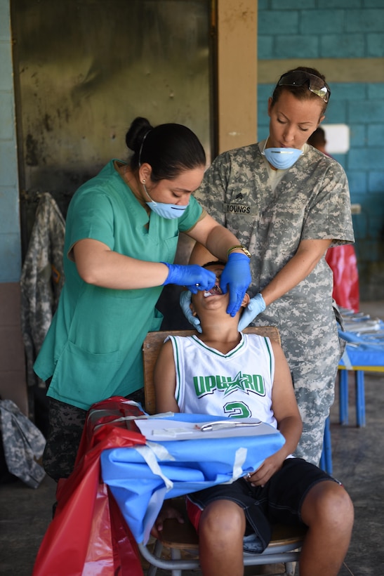 Honduran Army 2nd Lt. Ana Urbina (left) and U.S. Army Sgt. Charissa Youngs, Joint Task Force-Bravo Medical Element, perform a tooth extraction on a young boy during a Medical Readiness Training Exercise in Corinto, Cortes, Feb. 17, 2017.  Besides preparation in the medical field, JTF-Bravo personnel also had the opportunity to develop ties with local health providers, military and other organizations.  (U.S. Army photo by Maria Pinel)