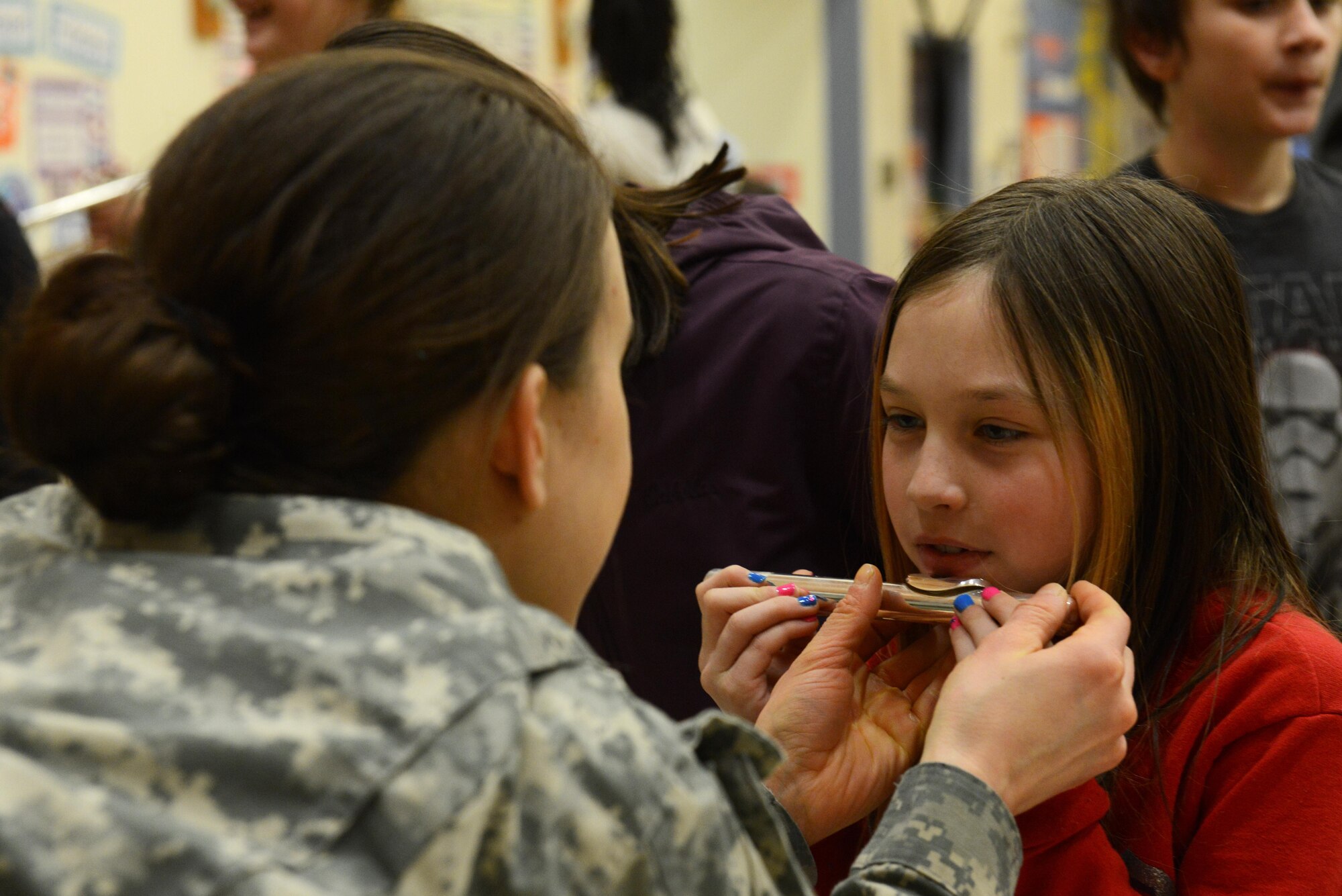 Specialist Sarah Gibson, flute player with the 9th Army Band group ‘Frigid Brass,’ teaches a child how to use the mouthpiece of a flute at Orion Elementary School, Joint Base Elmendorf-Richardson, Alaska, Feb. 21, 2017. ‘Frigid Brass’ performed many different genres of music and taught the children the first steps in playing each instrument to spark an interest in the musical arts. 