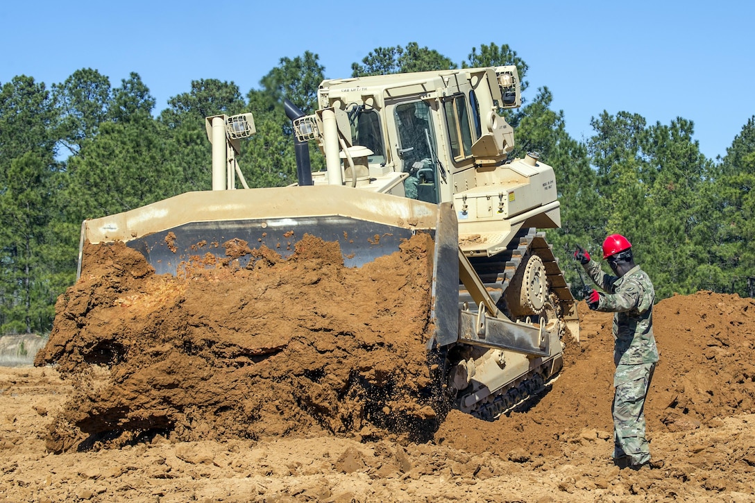Army Staff Sgt. Edwin Williams directs a crawler tractor operator during a construction engineer course at McCrady Training Center in Eastover, S.C., Feb. 26, 2017. During the course, soldiers learned to maneuver the tractor for a variety of tasks, including flat-bottom ditching, a defensive formation to conceal tanks on the battlefield. Williams is an instructor assigned to the South Carolina Army National Guard, 218th Leadership Regiment. Army National Guard photo by Sgt. Brian Calhoun