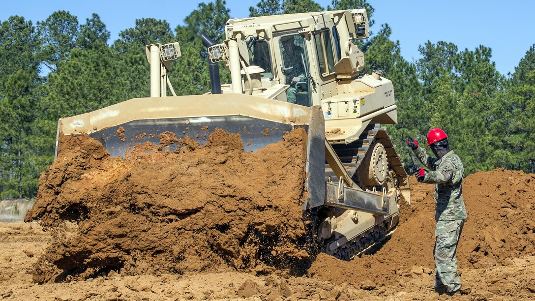 Army Staff Sgt. Edwin Williams directs a crawler tractor operator during a construction engineer course at McCrady Training Center in Eastover, S.C., Feb. 26, 2017. During the course, soldiers learned to maneuver the tractor for a variety of tasks, including flat-bottom ditching, a defensive formation to conceal tanks on the battlefield. Williams is an instructor assigned to the South Carolina Army National Guard, 218th Leadership Regiment. Army National Guard photo by Sgt. Brian Calhoun