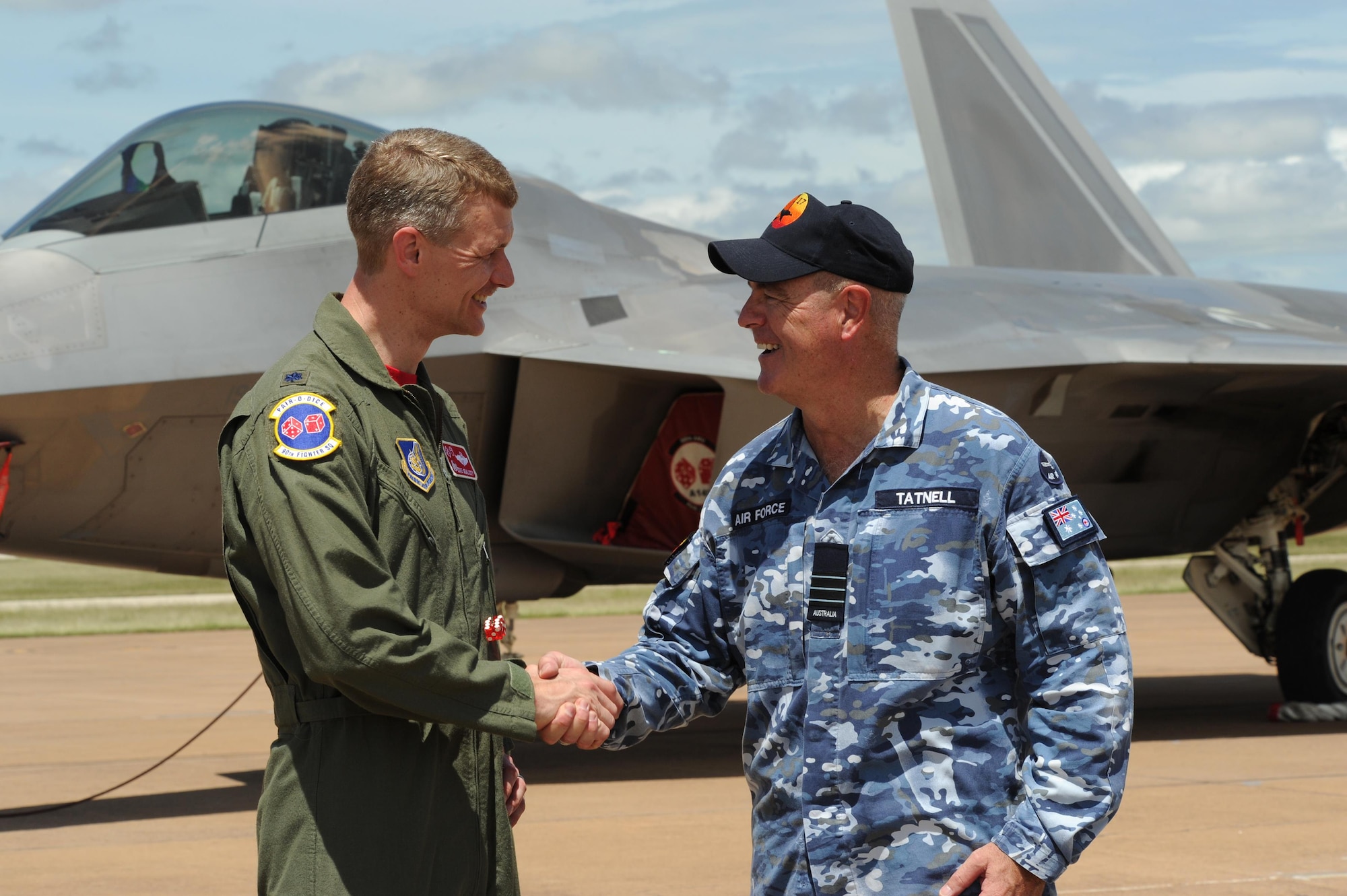 U.S. Air Force Lt. Col. David Skalicky, 90th Fighter Squadron commander, and Wing Commander Andrew Tatnell, Royal Australian Air Force Base Tindal Senior Australian Defence Force Officer, shake hands in front of a U.S. F-22 Raptor at RAAF Base Tindal, Australia, Feb. 24, 2017. Twelve F-22 Raptors and approximately 200 U.S. Air Force Airmen are in Australia as part of the Enhanced Air Cooperation, an initiative under the Force Posture Agreement between the U.S. and Australia. (U.S. Air Force photo by Staff Sgt. Alexander Martinez)