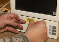 Tech. Sgt. Linsey McCluskey, 5th Medical Support Squadron medical maintenance NCO-in-charge, places a maintenance sticker on a vital signs monitor at the 5th Medical Group clinic at Minot Air Force Base, N.D., Feb. 8, 2017. All biomedical equipment is scheduled for maintenance every six months. (U.S. Air Force photo/Airman 1st Class Alyssa M. Akers)