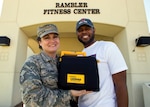 Senior Master Sgt. Brandy Sharp poses for a photo in front of the Rambler Fitness Center on Joint Base San Antonio-Randolph, Texas, with Master Sgt. Ernest Winston and the exact automated external defibrillator she used to save his life. Sharp is the 359th Medical Support Squadron superintendent; Winston is a 359th Medical Group medical technician. (U.S. Air Force photo/Staff Sgt. Kevin Iinuma)