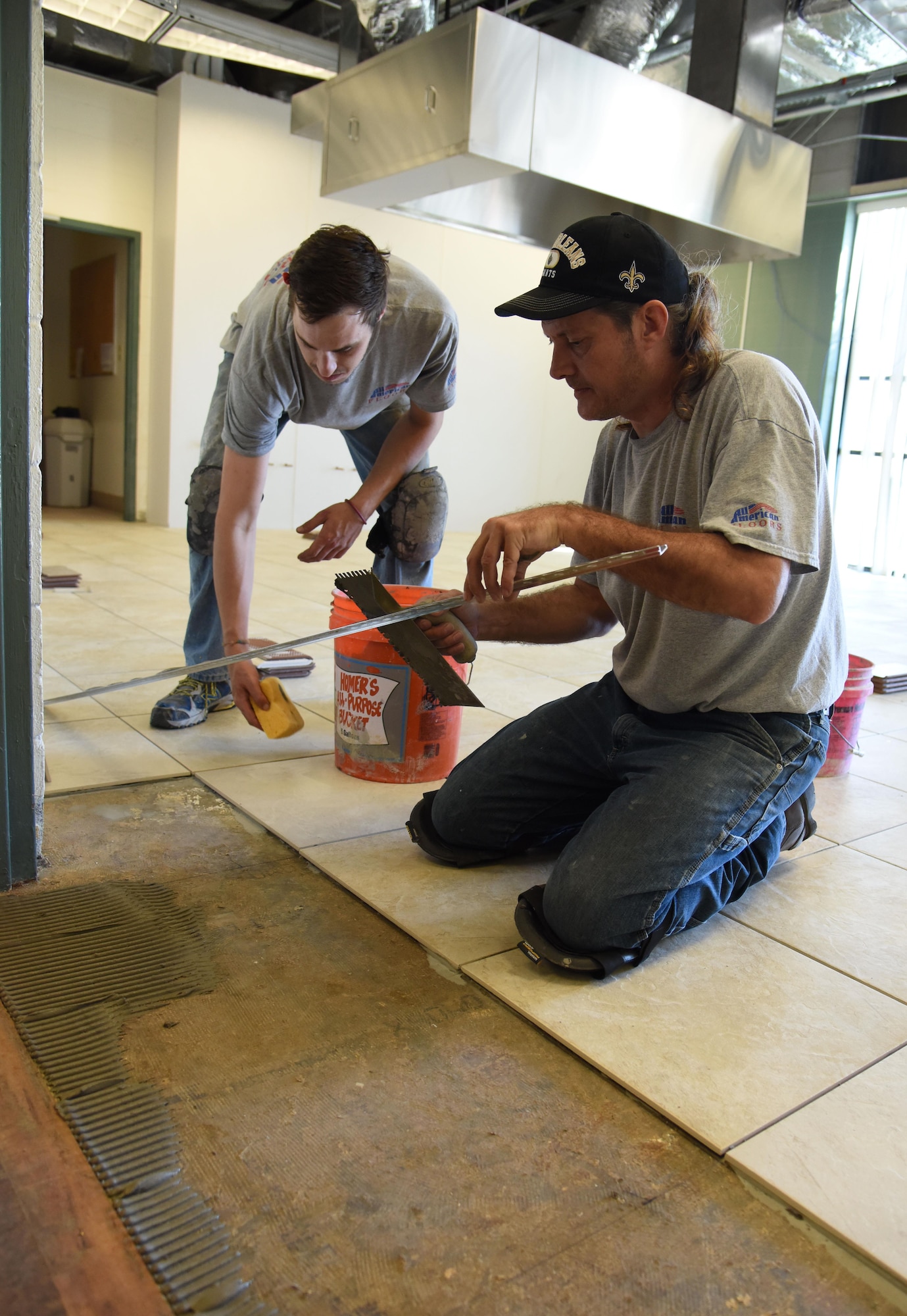 Ashton Hogue and David Kuzur, All American Floors tile installers, lay tile in the kitchen at the McBride Commons Feb. 23, 2017, on Keesler Air Force Base, Miss. The McBride Commons renovation project will transition the former base library into a common area for those with, which will include a children’s library, computer stations, engraving, framing, marketing and print shops and a full kitchen. The planned completion date for the nine-month project is May 2017. (U.S. Air Force photo by Kemberly Groue)