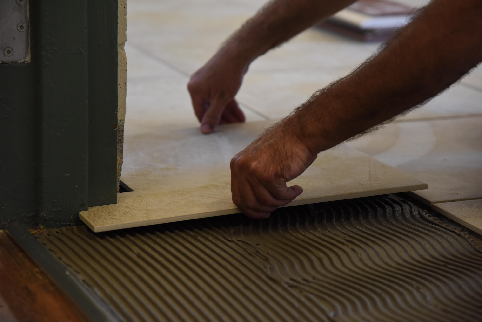 David Kuzur, All American Floors tile installer, lays a piece of tile in the kitchen at the McBride Commons Feb. 23, 2017, on Keesler Air Force Base, Miss. The McBride Commons renovation project will transition the former base library into a common area for those with, which will include a children’s library, computer stations, engraving, framing, marketing and print shops and a full kitchen. The planned completion date for the nine-month project is May 2017. (U.S. Air Force photo by Kemberly Groue)
