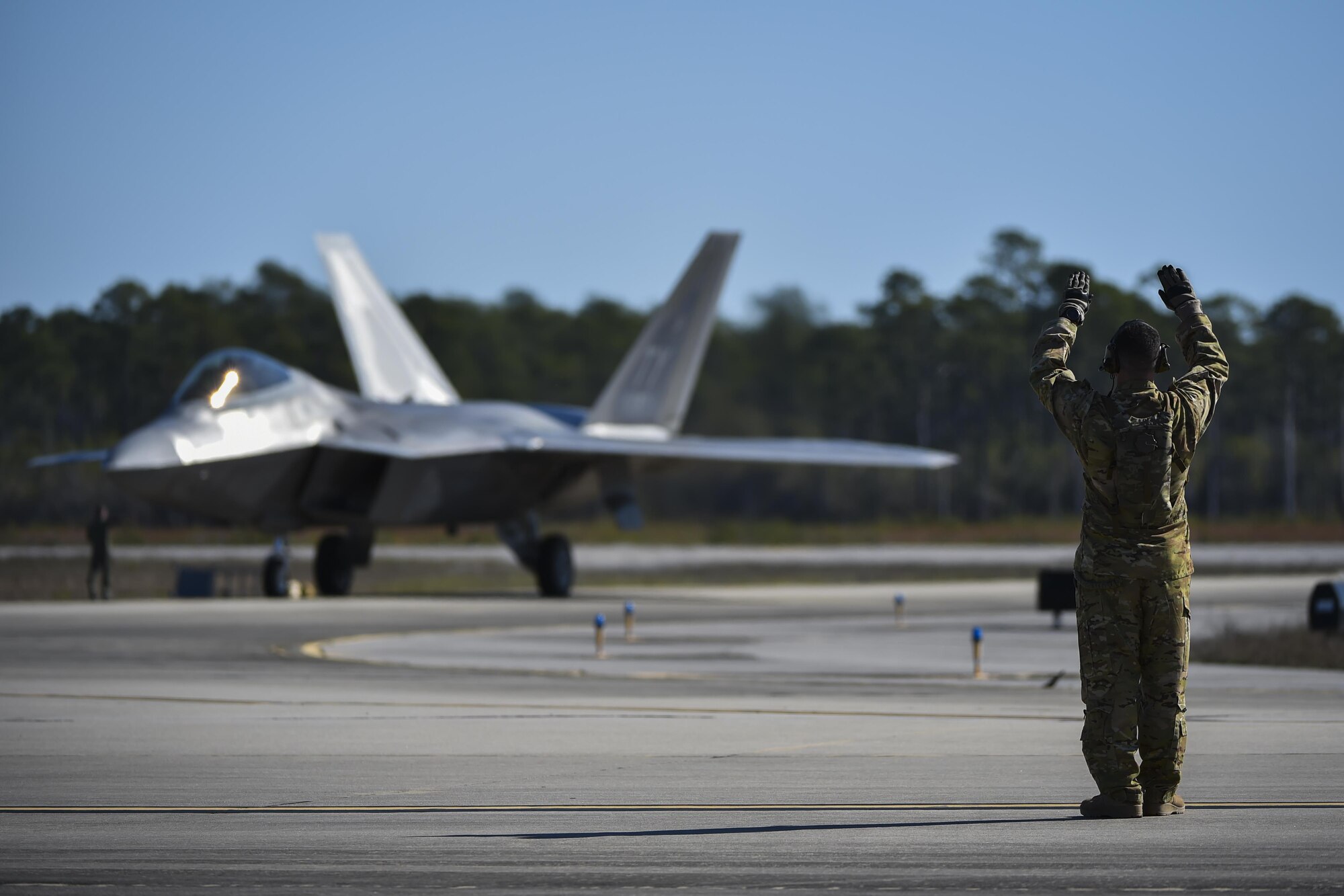 An F-22 Raptor assigned to the 95th Fighter Squadron, Tyndall Air Force Base, Fla., is marshalled in by a forward area refueling point Air Commando with the 1st Special Operations Logistic Readiness Squadron at Hurlburt Field, Fla., Feb. 26, 2017. FARP Airmen refueled three F-22s from an MC-130J Commando II tanker aircraft assigned to the 9th Special Operations Squadron, Cannon AFB, N.M., during the operation. The F-22 Raptor is the Air Force's newest fighter aircraft, combining stealth, supercruise, maneuverability and integrated avionics. (U.S. Air Force photo by Airman 1st Class Joseph Pick)