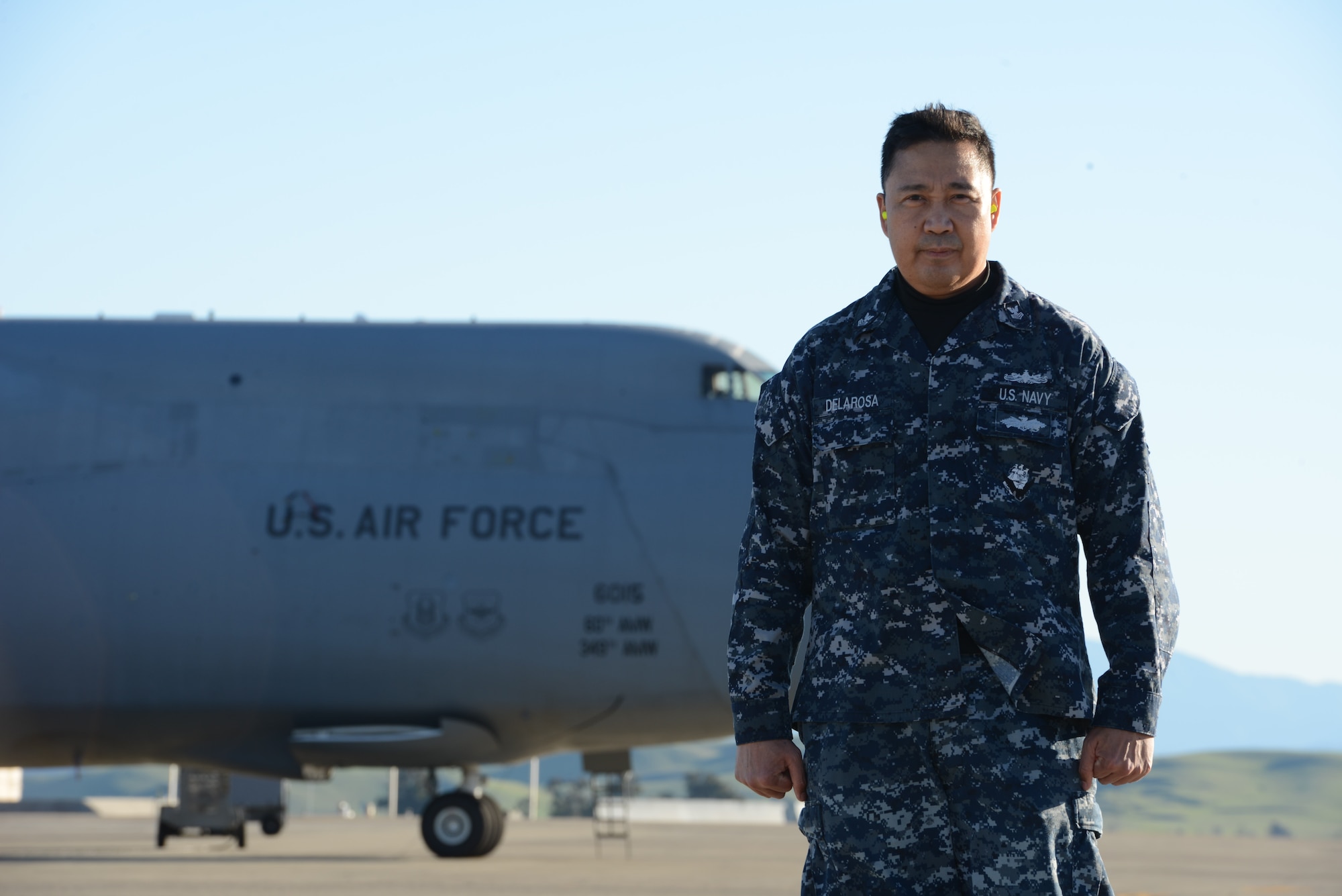 Logistics Specialist 1st Class Geronimo Delarosa, of Manila, Republic of the Philippines, poses in front of an Air Force C-5 Super Galaxy at Travis Air Force Base, Calif., Jan. 27, 2017. Delarosa is assigned to the only forward-deployed aircraft carrier, the USS Ronald Reagan (CVN 76), and attached to the 60th Aerial Port Squadron at Travis. He provides stateside logistical support for the carrier. (U.S. Navy photo/Chief Mass Communication Specialist Xander Gamble/Released)