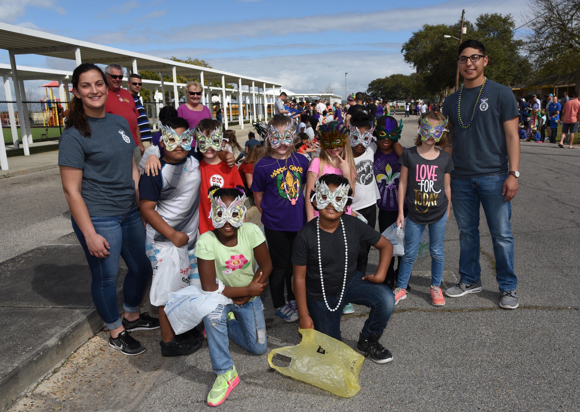 Airman Gabrielle Wychoff, 81st Security Forces Squadron administrator, and Airman 1st Class Eric Martinez, 81st SFS entry controller, pose for a photo with students at Jeff Davis Elementary School during its Mardi Gras Parade, Feb. 24, 2017, Biloxi, Miss. The Keesler AFB Honor Guard and other base personnel also participated in the festivities. (U.S. Air Force photo by Kemberly Groue)