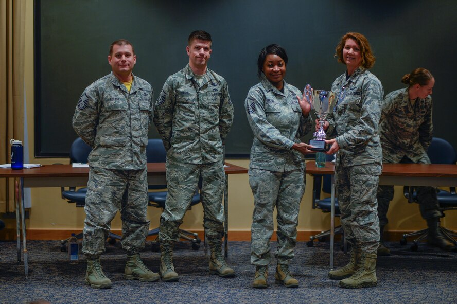 Col. Robyn Slade (right), Individual Mobilization Augmentee to the 50th Space Wing commander, presents the Schriever Debate trophy to the Top III Council following the debate at Schriever Air Force Base, Colorado, Friday, Feb. 24, 2017. Master Sgts. Matt Lofton, John Harms and Kendra Bryan persuaded three of the five judges with their argument favoring the return of a warrant officer corps to the Air Force. (U.S. Air Force photo/Christopher DeWitt)