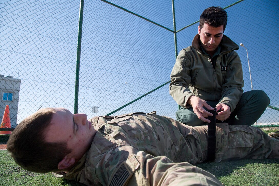 A Kurdish security force member, right, applies a practice tourniquet to Army Spc. Denis Moyer during a tactical combat casualty care class near Erbil, Iraq, Feb. 19, 2017. Moyer is assigned to the 82nd Airborne Division’s Company B, 2nd Battalion, 325th Airborne Infantry Regiment, 2nd Brigade Combat Team. Army photo by Spc. Craig Jensen