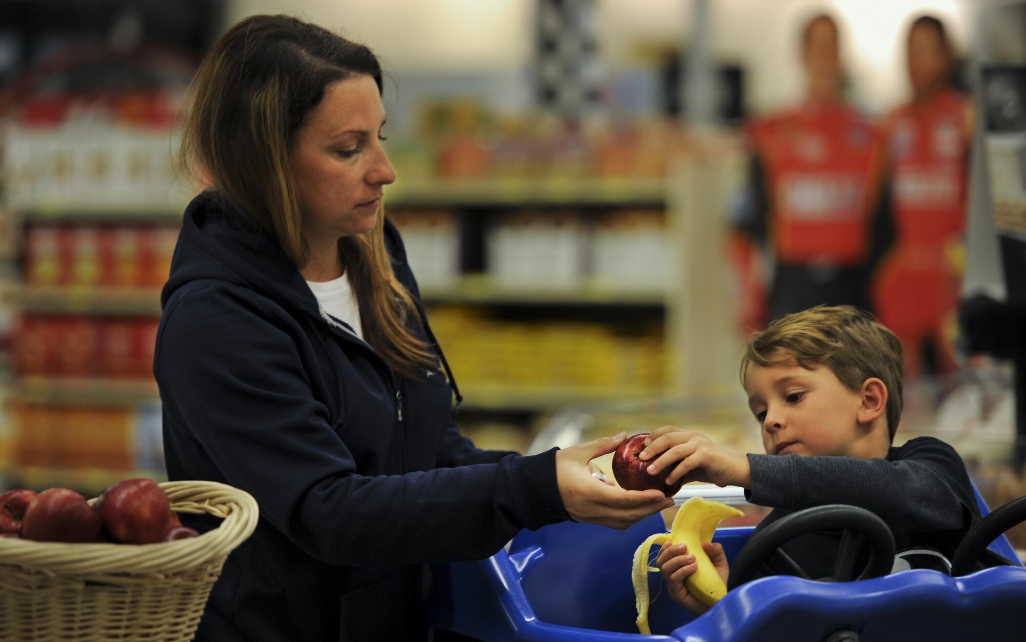 Master Sgt. Jodi Zellers, a contracting officer with the Air Force Test Center at Eglin Air Force Base, hands her son an apple at Hurlburt Field, Fla., Feb. 22, 2017. The Health and Wellness Center staff held an event at the commissary to teach the community habits for a heart-healthy life in recognition of National Heart Health Month. (U.S. Air Force photo by Airman 1st Class Dennis Spain)