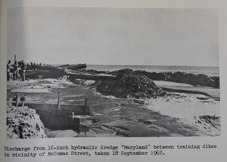 Sand is pumped onto the beach near what is likely meant to be McComas Avenue, near 123rd Street now. The training dikes are barriers of sand used to help keep freshly pumped sand in the area while allowing water to flow back to the Atlantic Ocean.