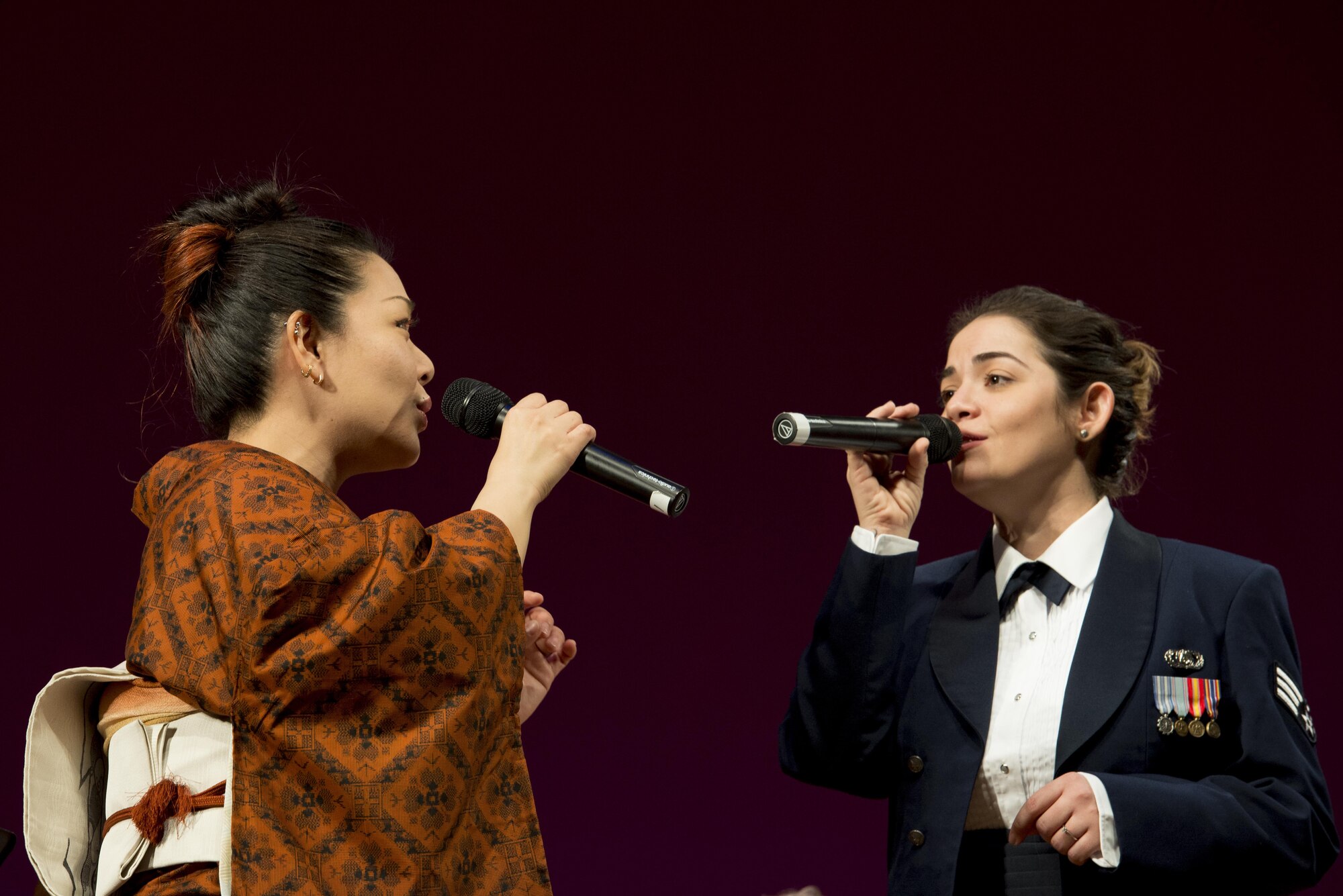 Miki Takahashi, Mizuho Youth Symphonic Band vocalist (Left), and Senior Airmen Maritzaida Amador, U.S. Air Force Band of the Pacific-Asia vocalist (Right), perform a duet during the Japan-U.S. Joint Concert Feb. 18, 2017, at the Mizuho View Park Sky Hall in Mizuho, Tokyo, Japan. The Mizuho Youth Symphonic Band and the U.S. Air Force Band of the Pacific-Asia mixed and played as one for the event. (U.S. Air Force photo by Airman 1st Class Donald Hudson)