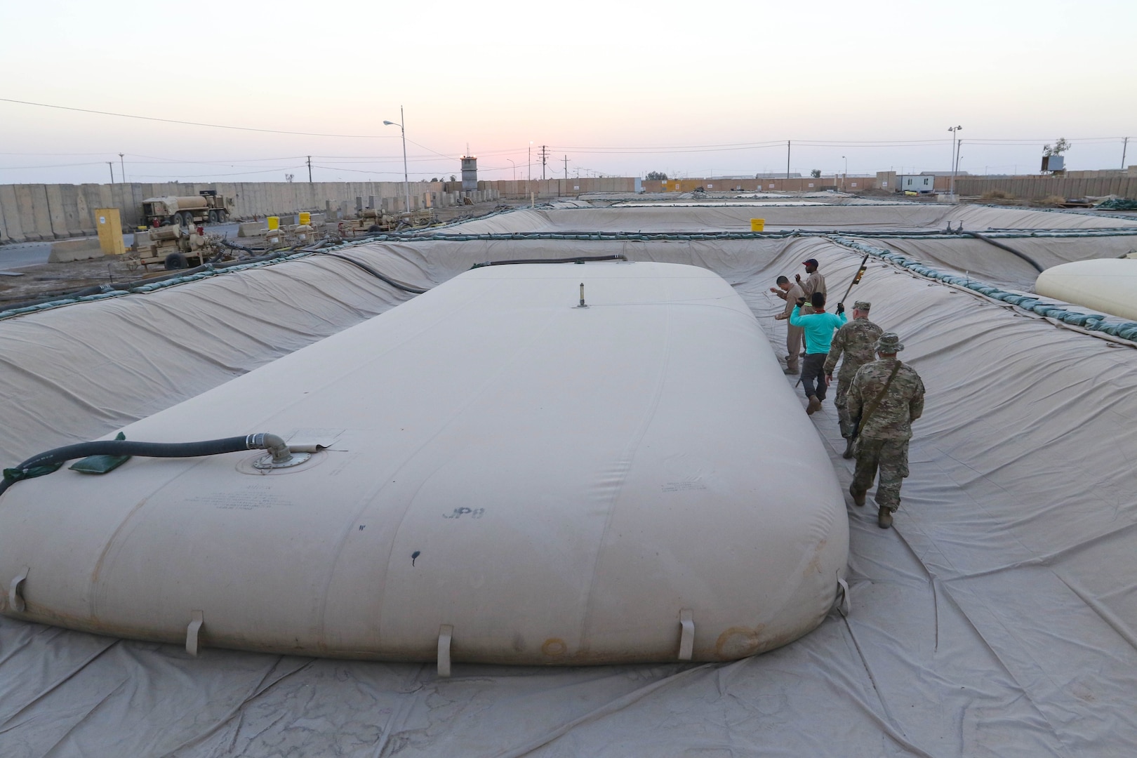 Inspectors General from the 1st Theater Sustainment Command-Operational Command Post inspect a fuel “bladder” at a fuel farm in central Iraq, recently. U.S. Army Central uses forward logistical elements to maintain fuel farms under contract with U.S. Army logistical specialists called contract representatives to ensure the operation is being conducted to the Army standard. (U.S. Army photo by Sgt. Brandon Hubbard, USARCENT Public Affairs)