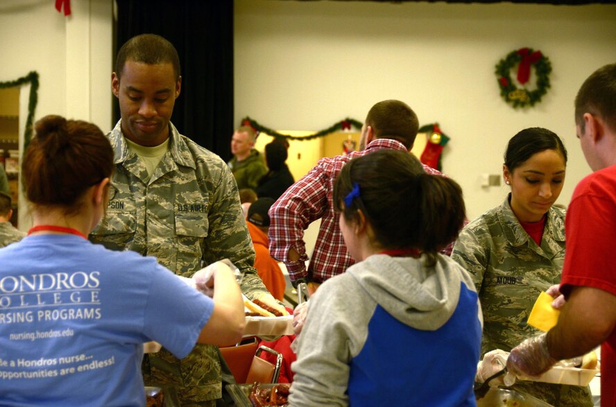 Airman 1st Class Michael Thompson, 87th Aerial Port Squadron personnel terminal journeyman, and Senior Airman Jowanda Ayoub, 445th Maintenance Group scheduler, stand in line to carry to-go plates for immobile veterans at the Dayton Veterans Affairs Medical Center holiday party, Dec. 3, 2016. Reservists, active-duty Airmen, ROTC cadets and civilians volunteered at the event. (U.S. Air Force photo/Staff Sgt. Joel McCullough)
