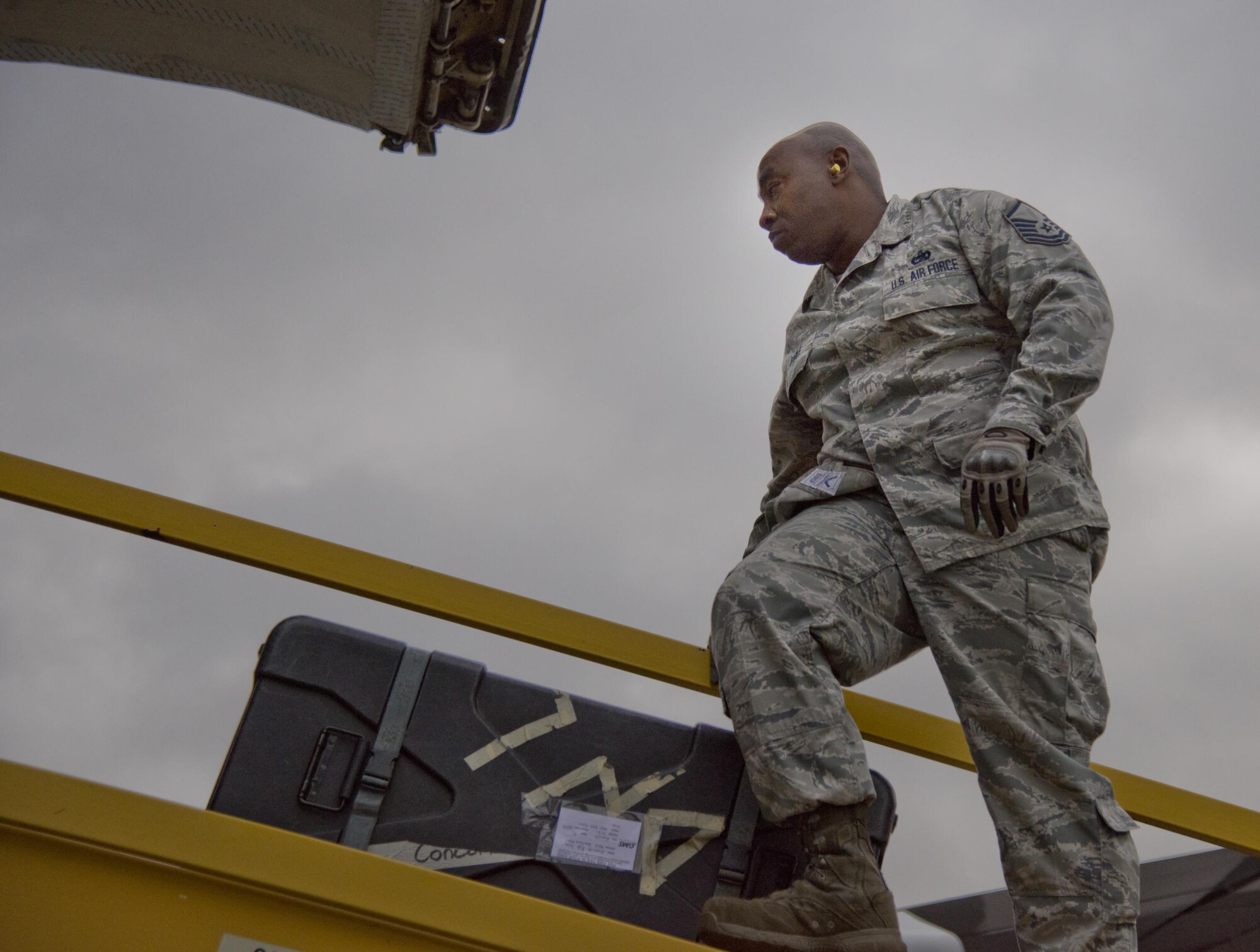 Master Sgt. Freddrick Earle, 96th Logistics Readiness Squadron, walks across the conveyer belt to guide equipment and luggage Dec. 29 on the flight line at Eglin Air Force Base, Fla. The crew of five loadmasters, also known as the ‘port dogs’ loaded nearly 82,000 pounds of equipment in less than two hours. The equipment belonged to the Niceville High School band students and staff members for their performance in the 2017 Tournament of Roses Parade in California. (U.S. Air Force photo/Kristin Stewart)