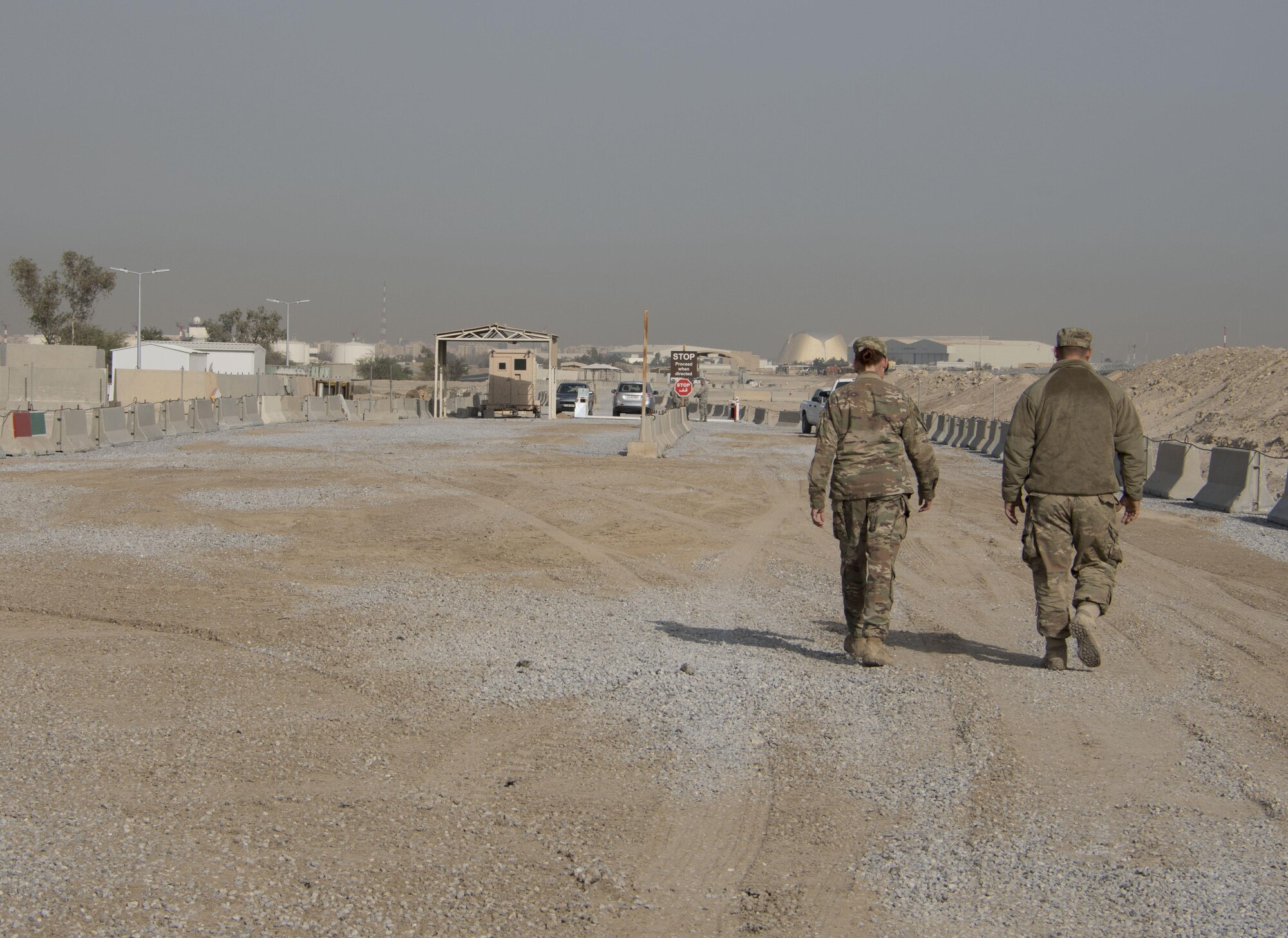 Tech. Sgt. Lora Ramos, left, and Senior Airman William Klein, right, of the 557th RED HORSE walk down a newly built road at an undisclosed location in Southwest Asia Dec. 30, 2016. The 387th Air Expeditionary Group enlisted the help of various squadrons and groups to complete the new road and entry control point in approximately four months. (U.S. Air Force photo/Senior Airman Andrew Park)